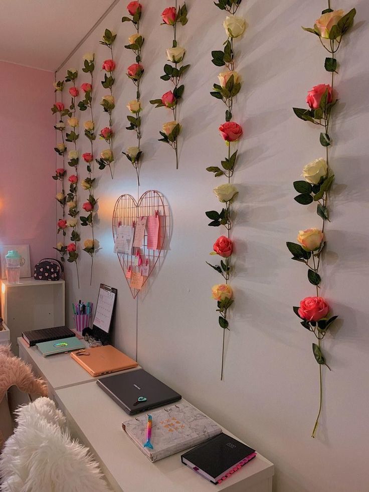 there is a desk with flowers on the wall and a laptop in front of it