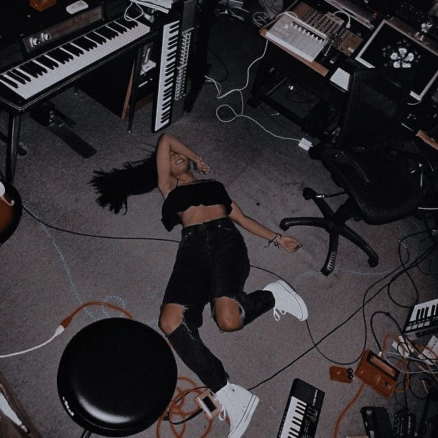 a woman laying on the floor in front of an assortment of musical instruments and keyboards