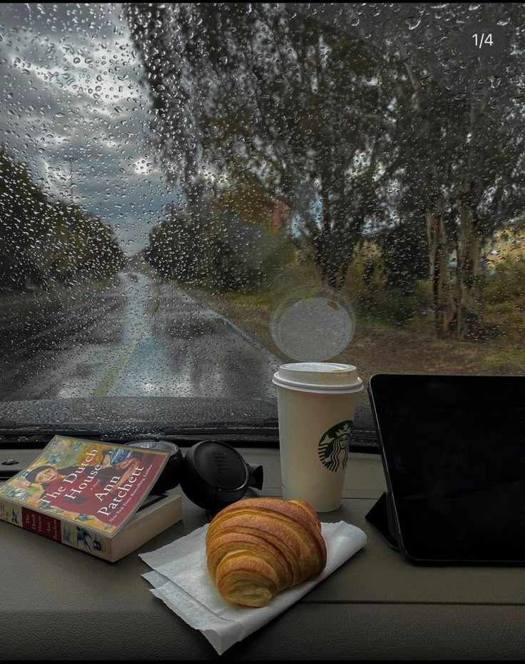 a cup of coffee and some pastries on a table in front of a window