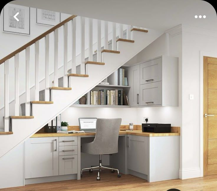 a computer desk under a stair case next to a bookshelf in a home office