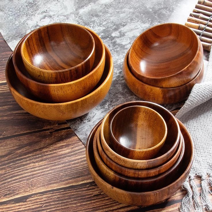 four wooden bowls sitting on top of a table next to a fork and napkin holder