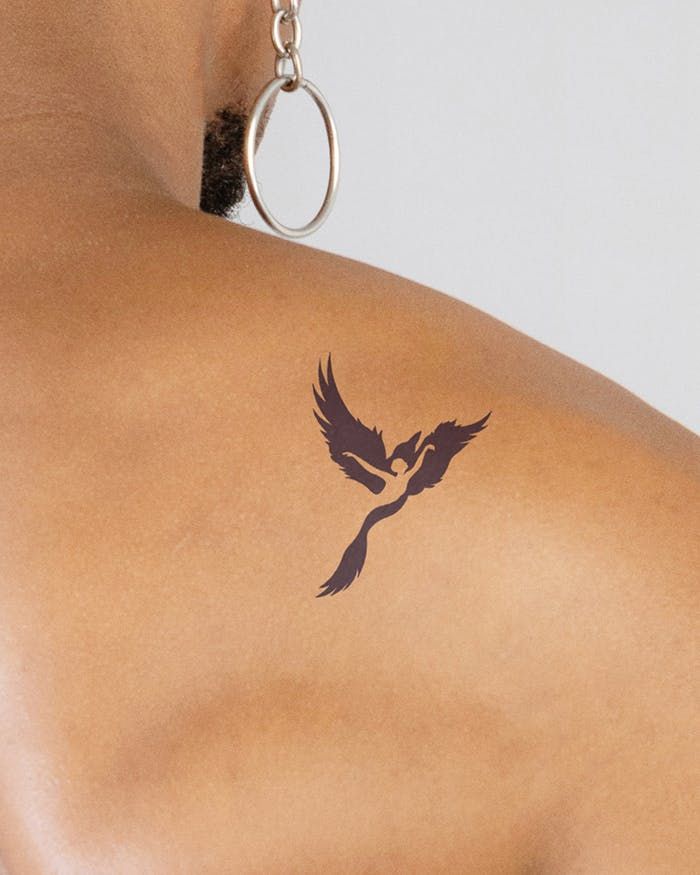 the back of a woman's shoulder with a bird tattoo on her left arm