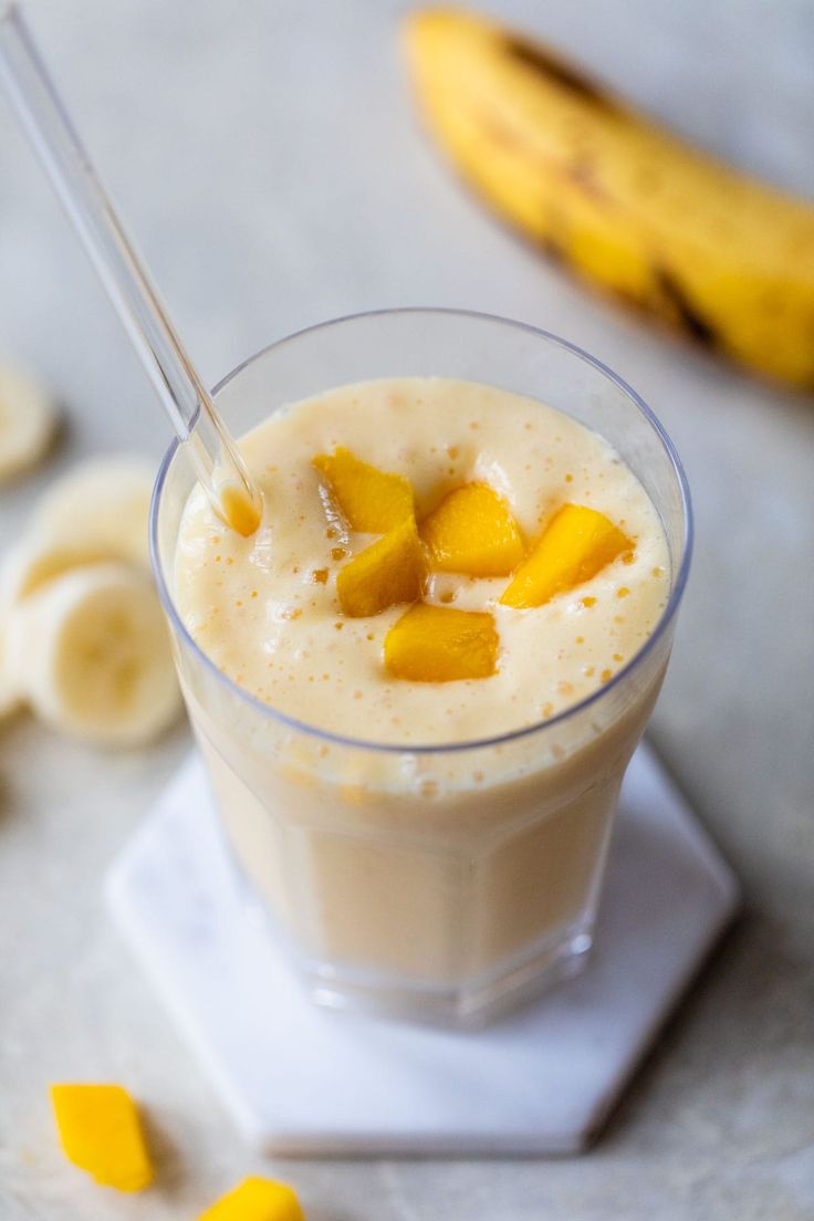 a smoothie in a glass topped with mango slices