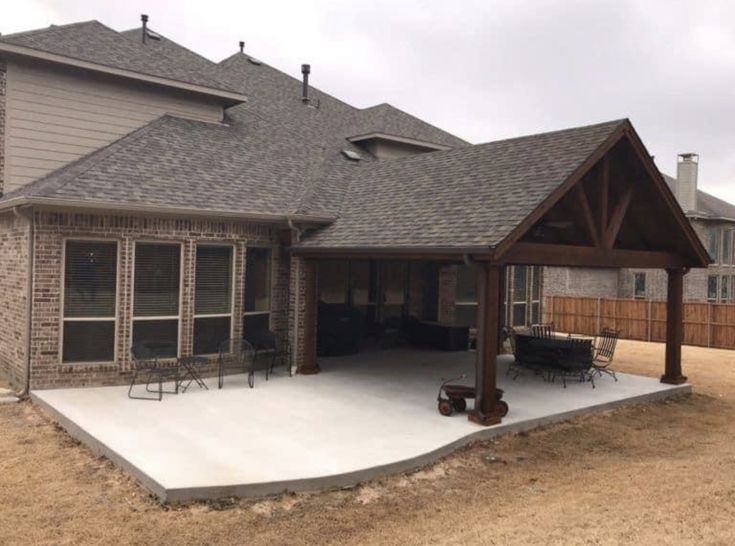 a house with a covered patio in the middle of it's back yard area