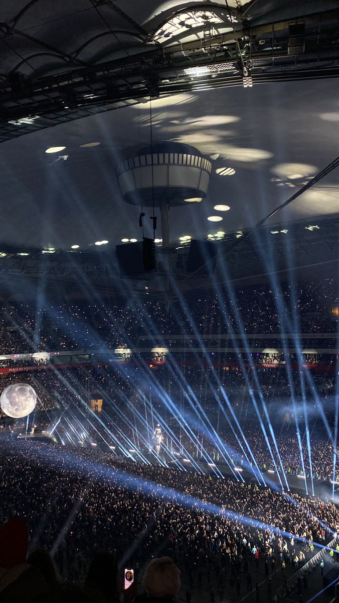 a large group of people in a stadium with bright lights on their faces and hands