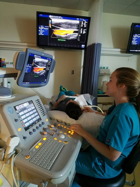 a woman sitting in a hospital bed next to a monitor with medical equipment on it