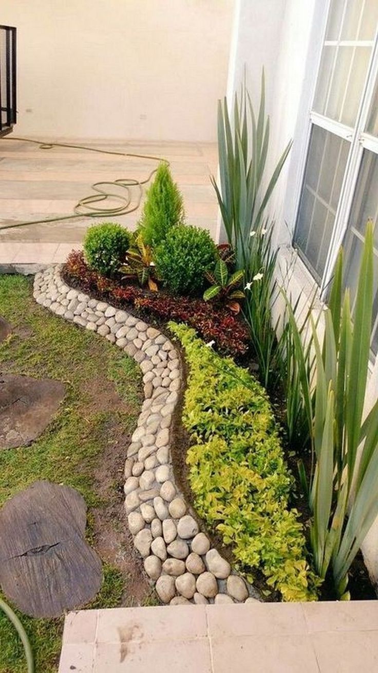 a small garden with rocks and plants in the front yard, next to a house