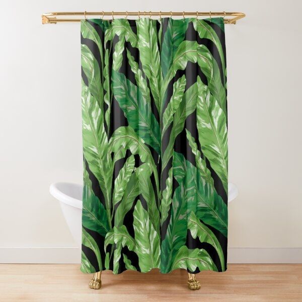 a shower curtain with green and black leaves on the outside, in front of a white bath tub