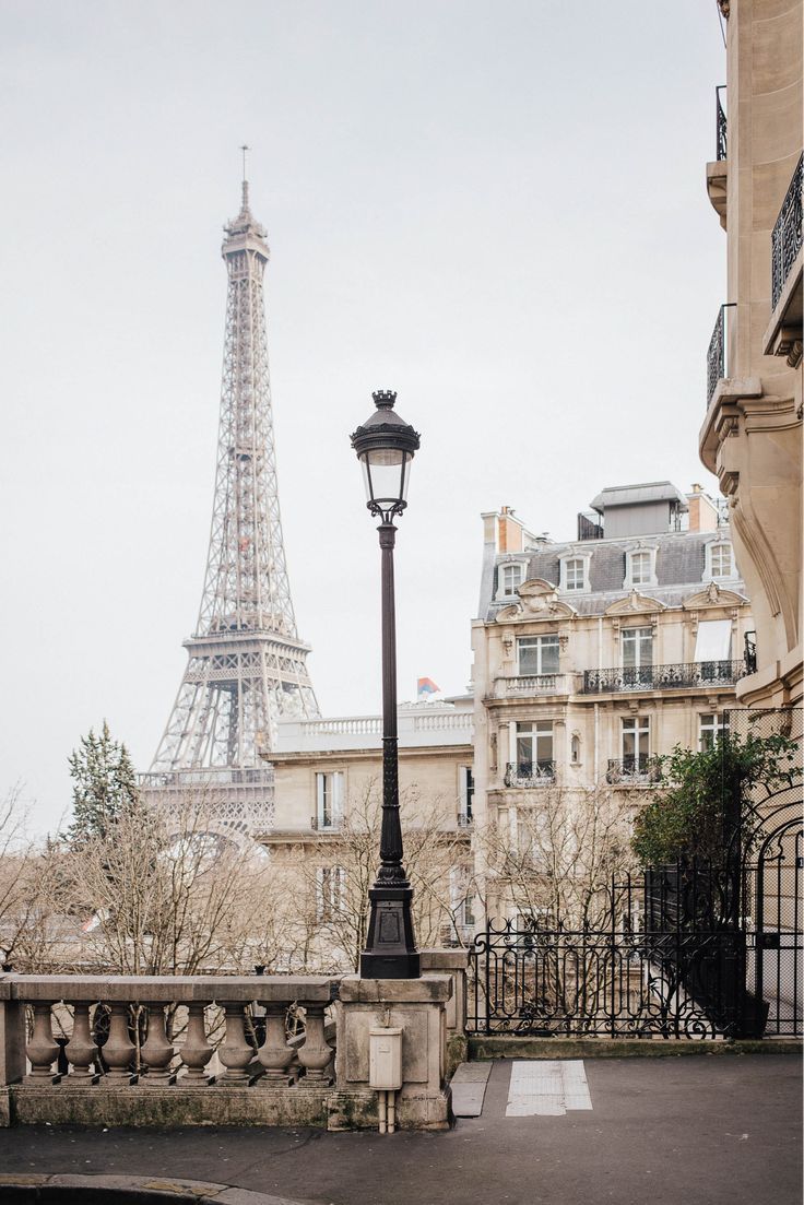 the eiffel tower is in the background of this street light and fenced area