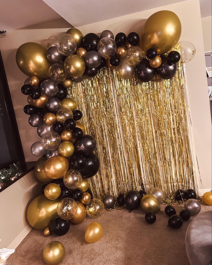 black and gold balloons are hanging from the ceiling