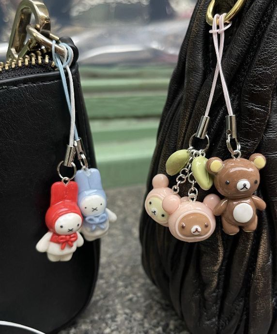 two purses with key chains attached to them sitting next to each other on a table