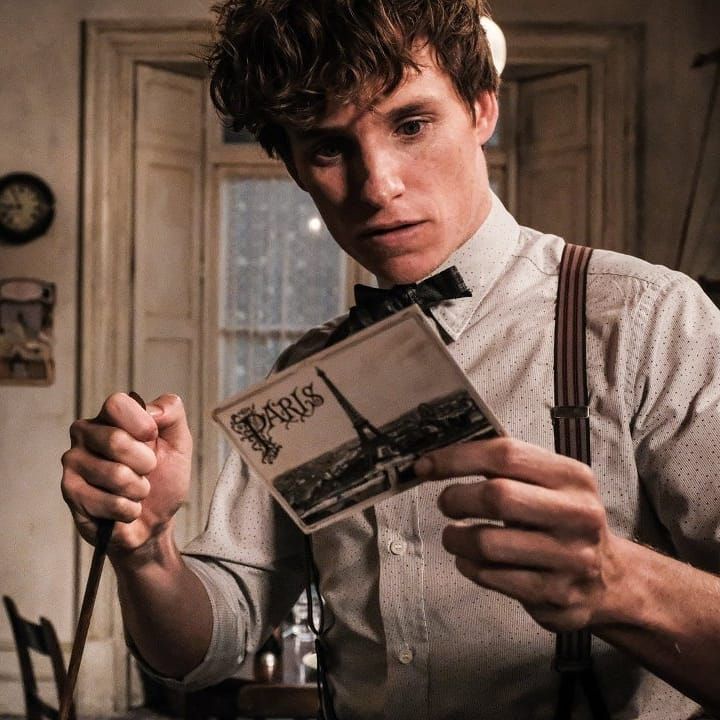 a young man in suspenders is looking at a box with the word harry potter on it