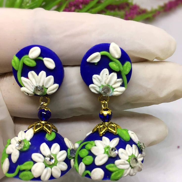 a pair of blue and white flowered earrings on a person's palm hand