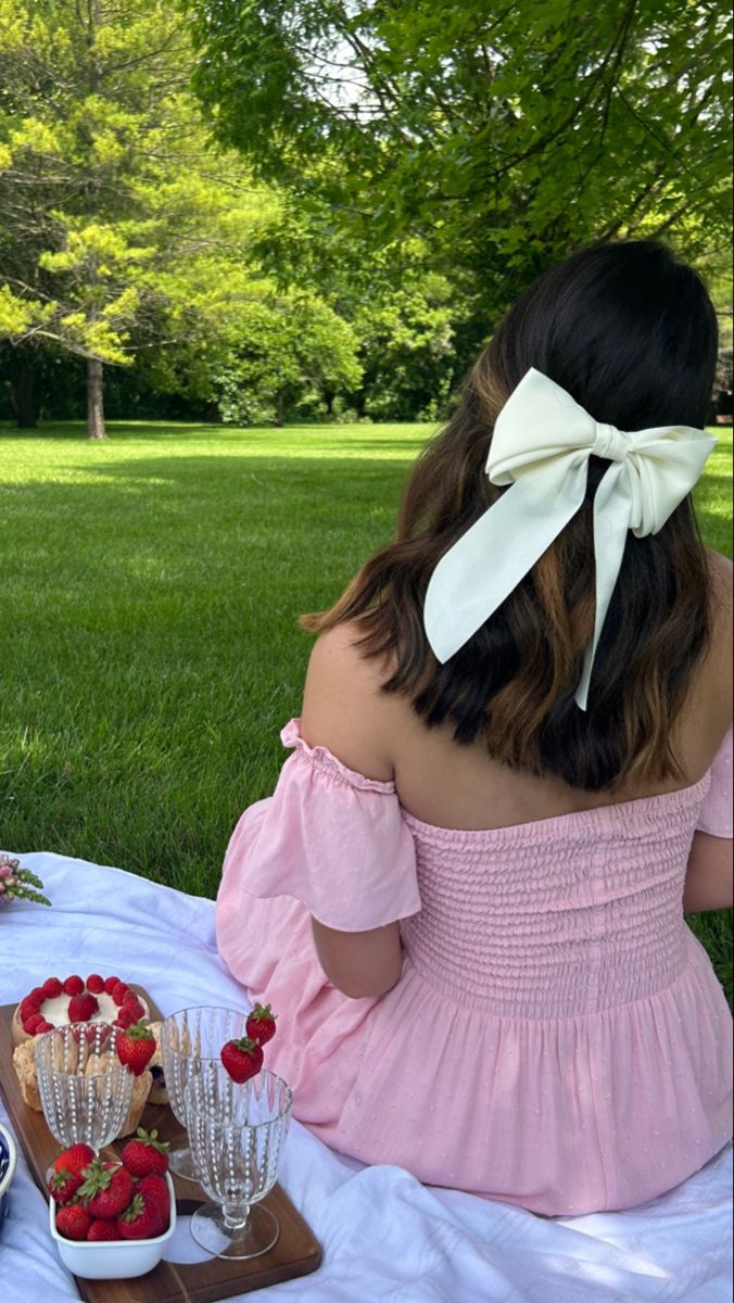 a woman sitting at a picnic table with strawberries