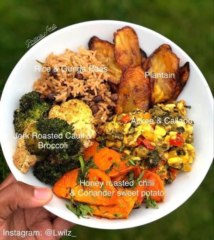 a white bowl filled with lots of different types of food on top of a green field