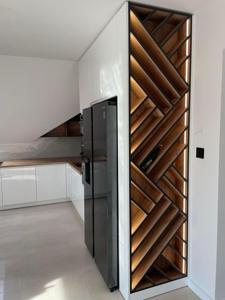 a modern kitchen with white cabinets and wood slats on the wall, along with a black refrigerator