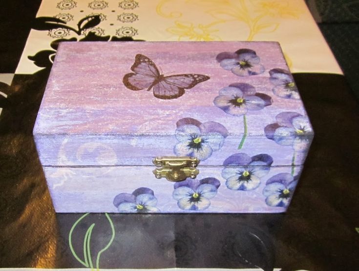 a wooden box with purple flowers and a butterfly painted on the lid is sitting on a table