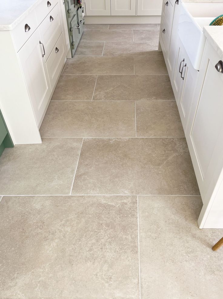 a kitchen with white cabinets and tile flooring