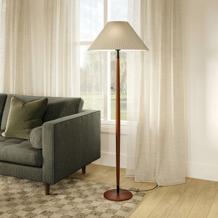 a living room scene with focus on the floor lamp and couch in front of the window