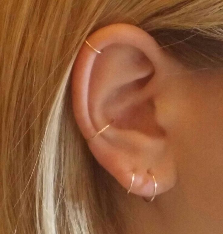 a woman's ear is shown with two small gold hoops