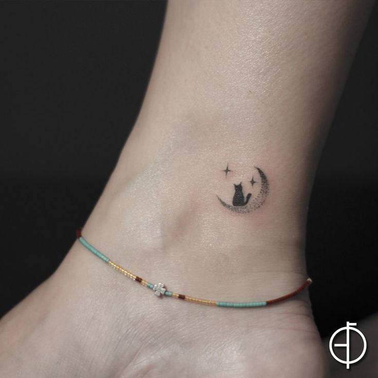 a small tattoo on the ankle of a woman's foot with a cat in the moon