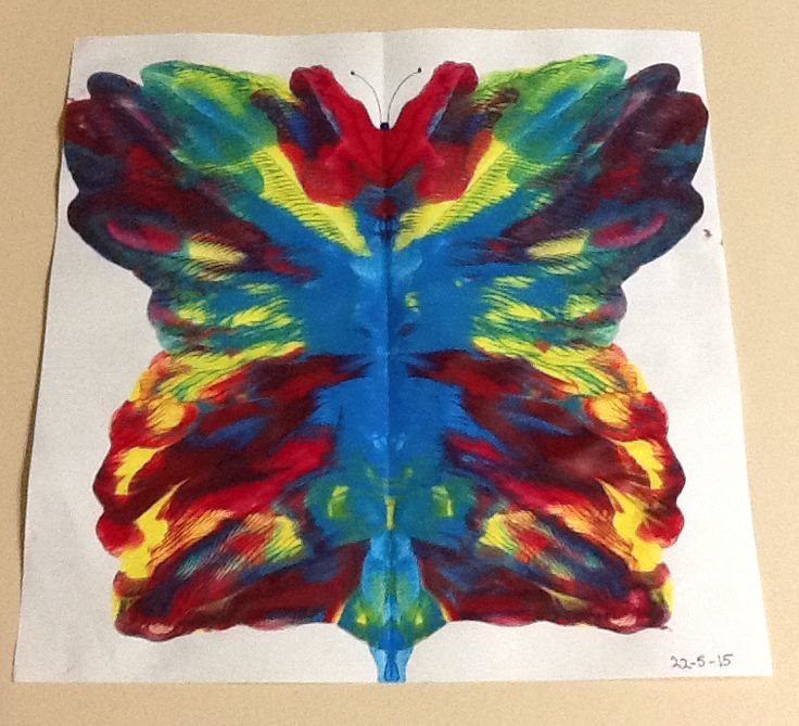 a colorful butterfly made out of paper on top of a white sheet with red, yellow and blue colors