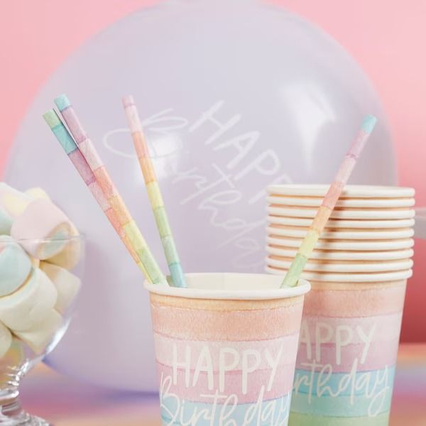 two cups with straws are sitting next to each other on a table in front of balloons