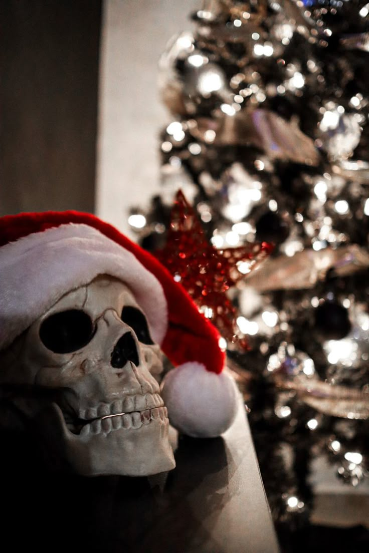 a skull wearing a santa hat on top of a table next to a christmas tree