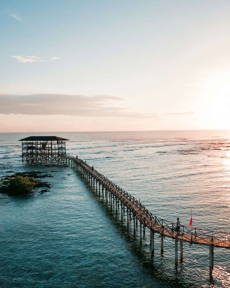 a long pier extending into the ocean at sunset