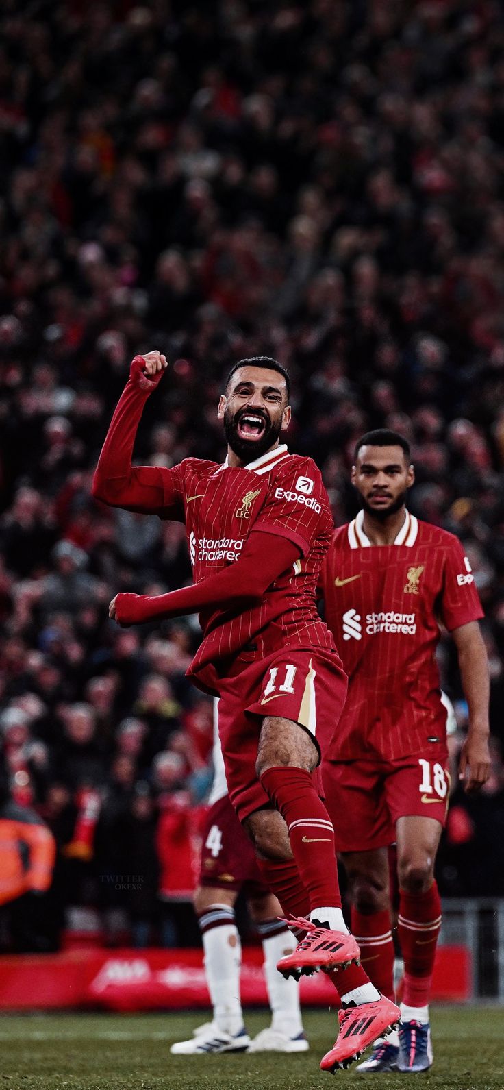 two men in red uniforms playing soccer on a field