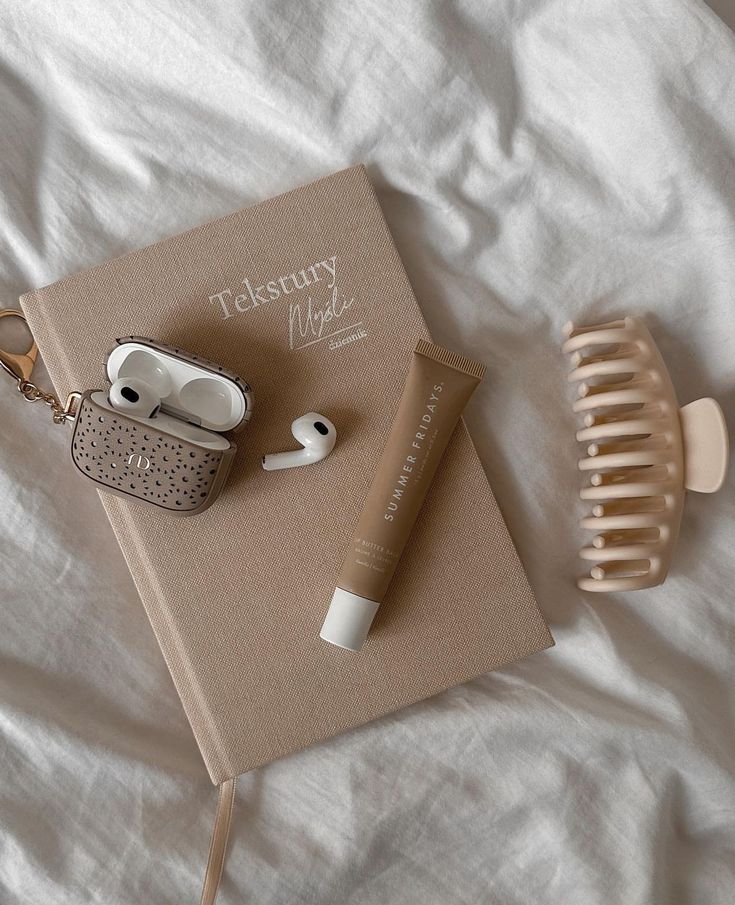 an open book with earbuds, hair brush and comb laying on top of it