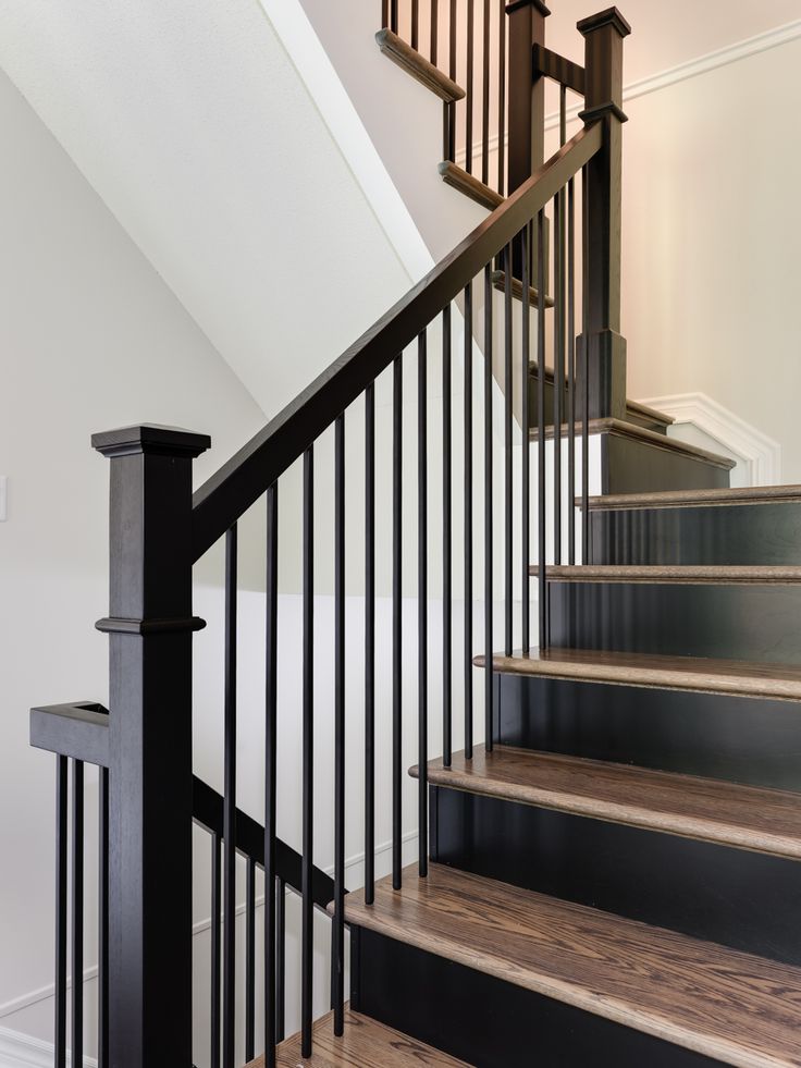 a staircase with black railing and wood handrails