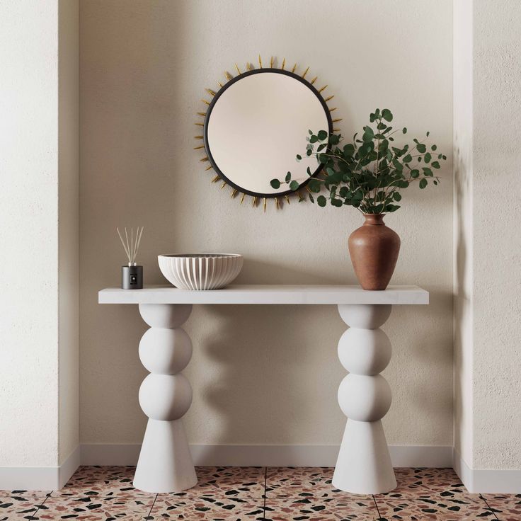 a white table with a mirror and vase on it