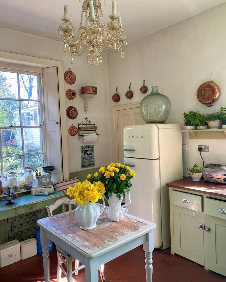 a kitchen with yellow flowers in vases on the table and an old fashioned refrigerator