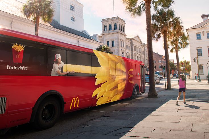 a mcdonald's bus is parked on the side of the street in front of some palm trees