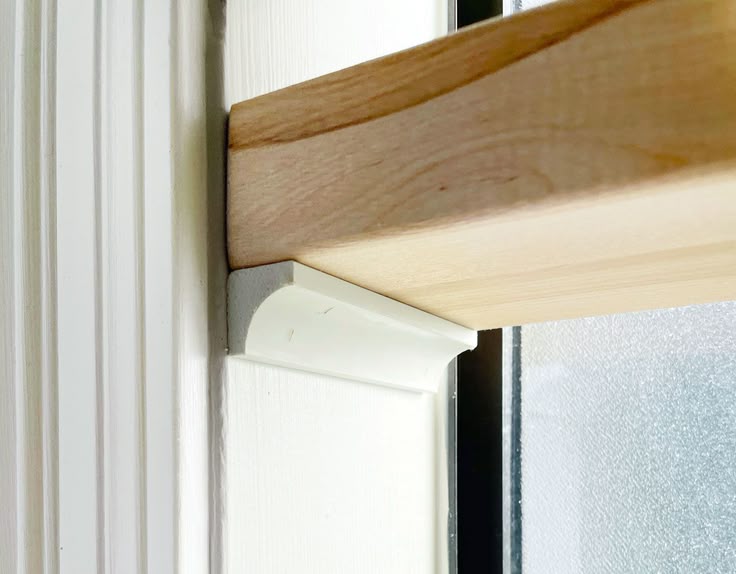 a close up of a wooden window seal on a white door with wood slats