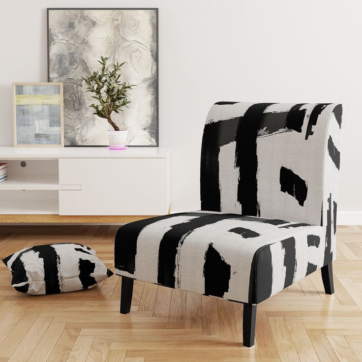 a black and white chair sitting on top of a hard wood floor next to a potted plant