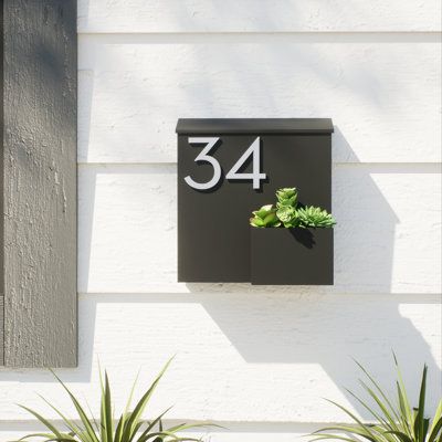 a house number sign mounted to the side of a building with plants growing out of it