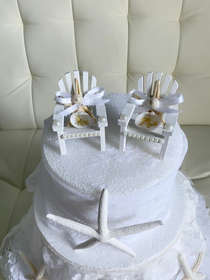 there is a wedding cake with two chairs on top and starfish decorations at the bottom