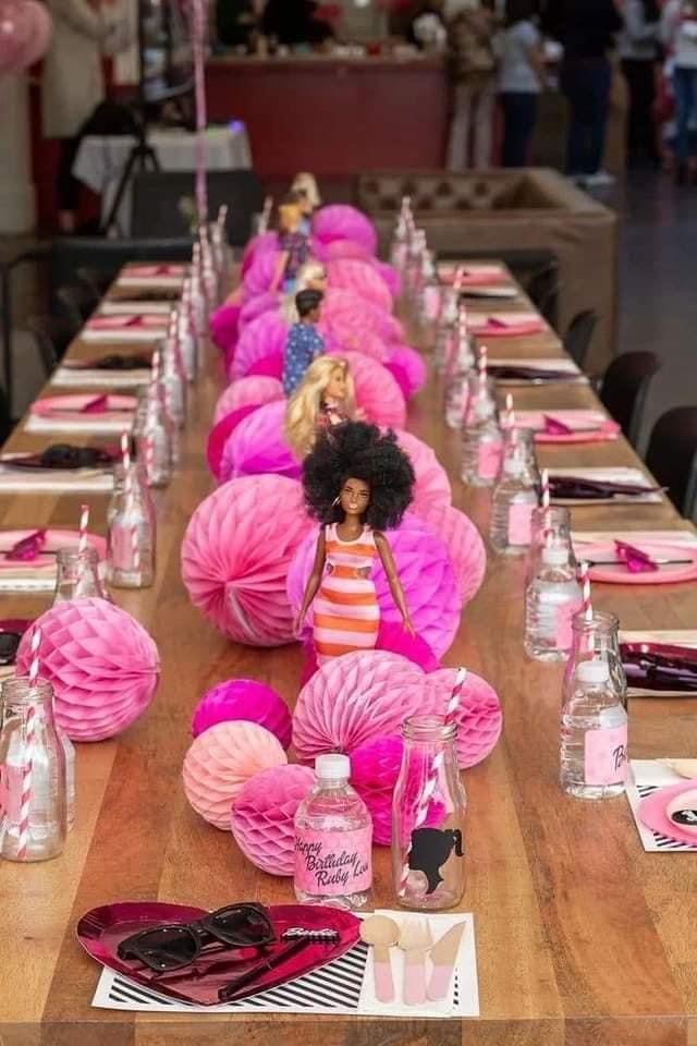 a long table with pink decorations and barbie dolls on it