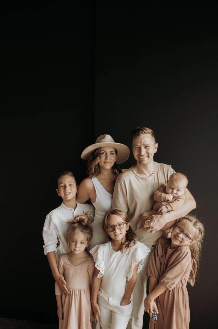 a group of people standing next to each other in front of a black wall with one person holding a baby