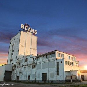 an old building with the word beans written on it's side in front of a sunset