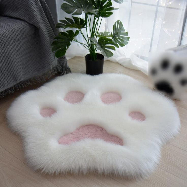 a white and pink animal paw rug on the floor next to a potted plant