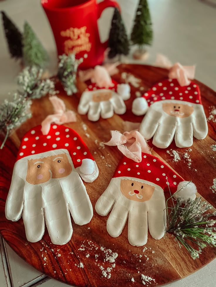 christmas decorations made to look like santas on a wooden platter next to a mug