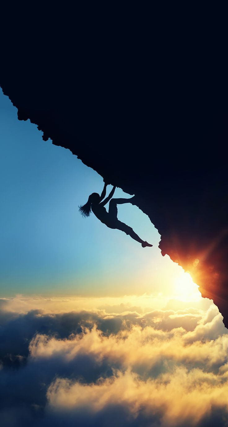 a person climbing up the side of a mountain with clouds in the foreground and sun behind them