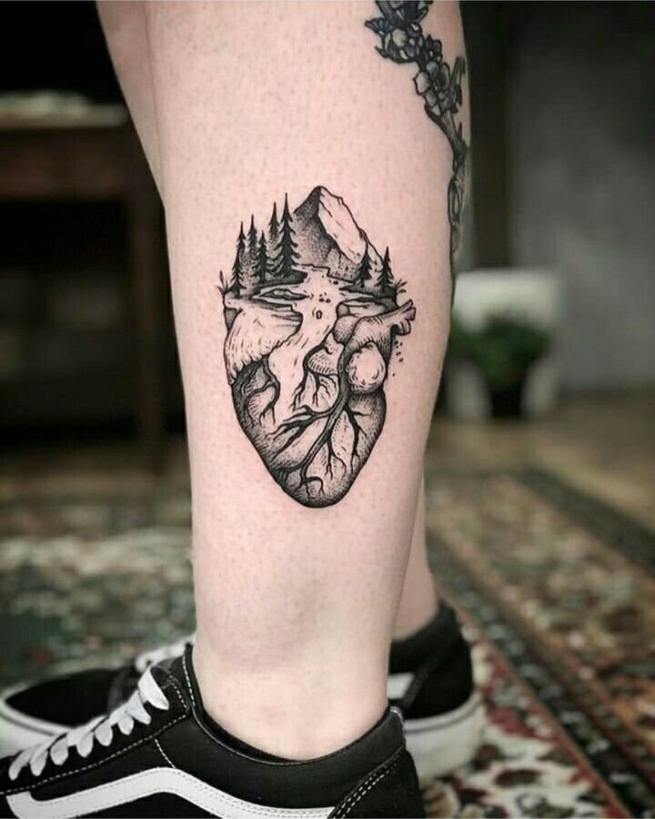 a black and white photo of a person with a heart tattoo on their leg