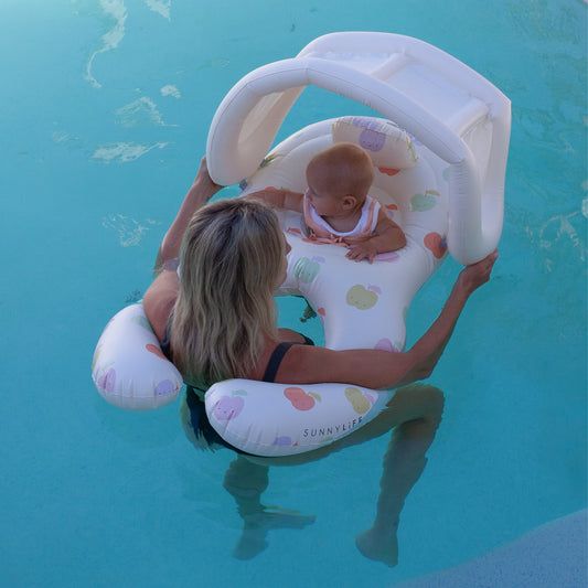 a woman holding a baby in an inflatable pool