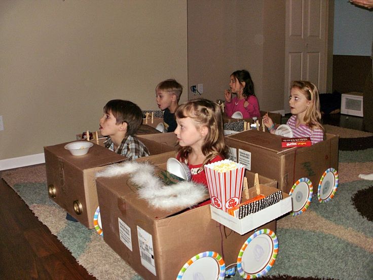 several children are sitting in cardboard cars with popcorn