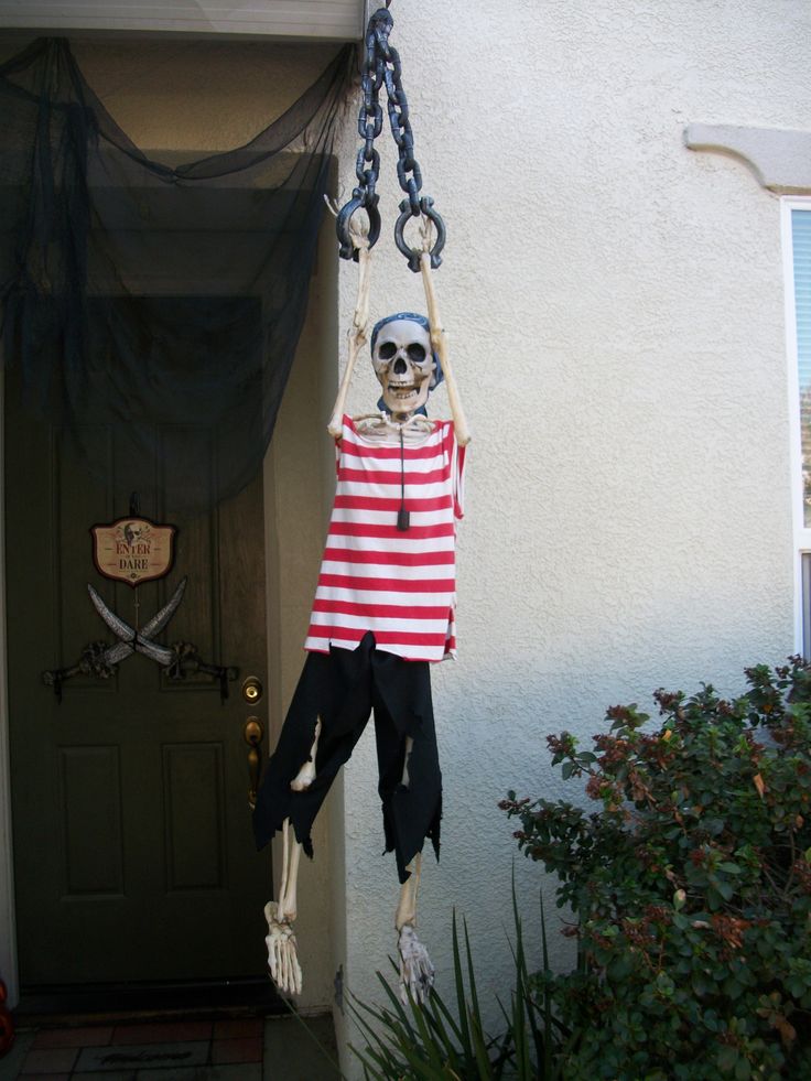 a skeleton hanging from a door with a red and white striped shirt on it's chest