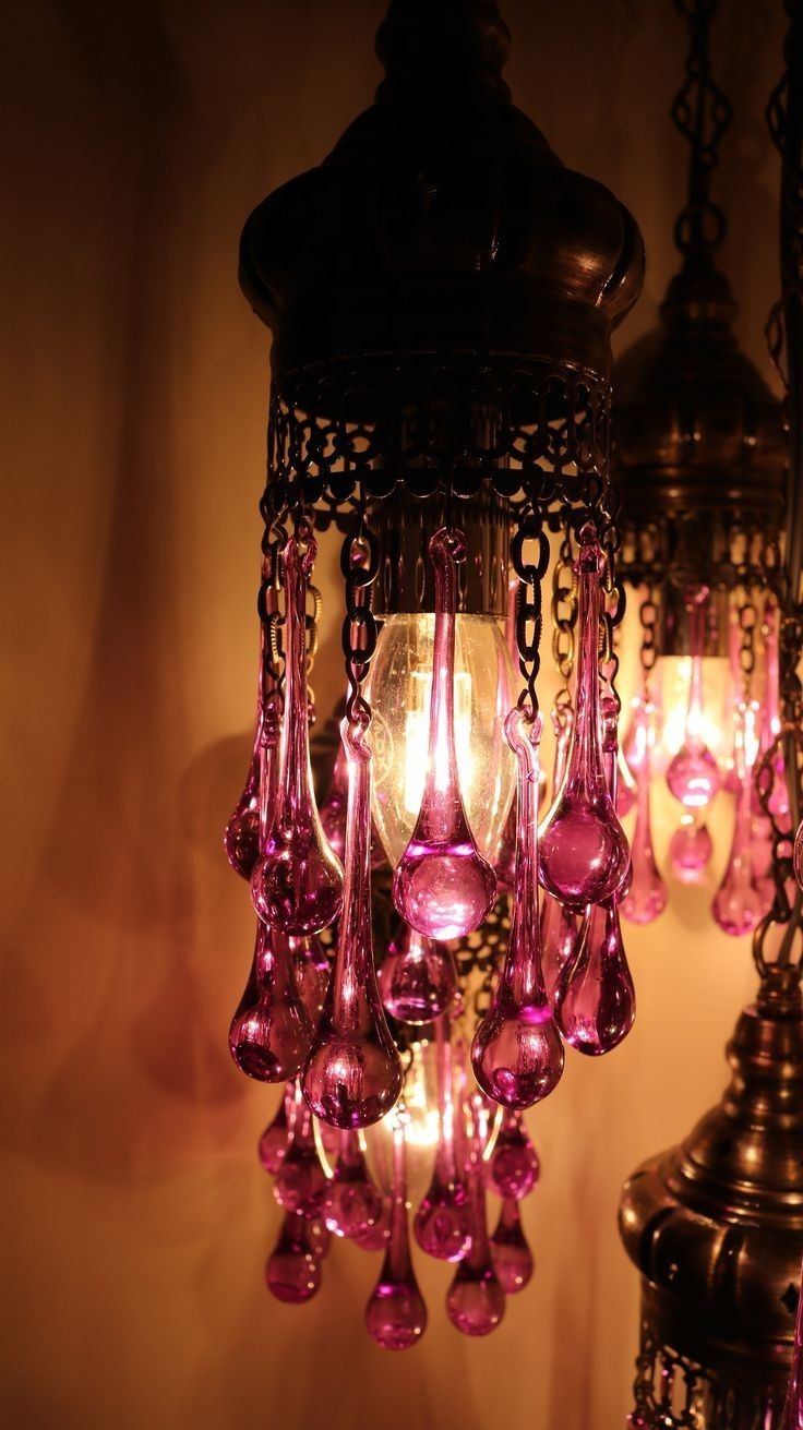 a chandelier hanging from the ceiling with pink glass beads and chains around it